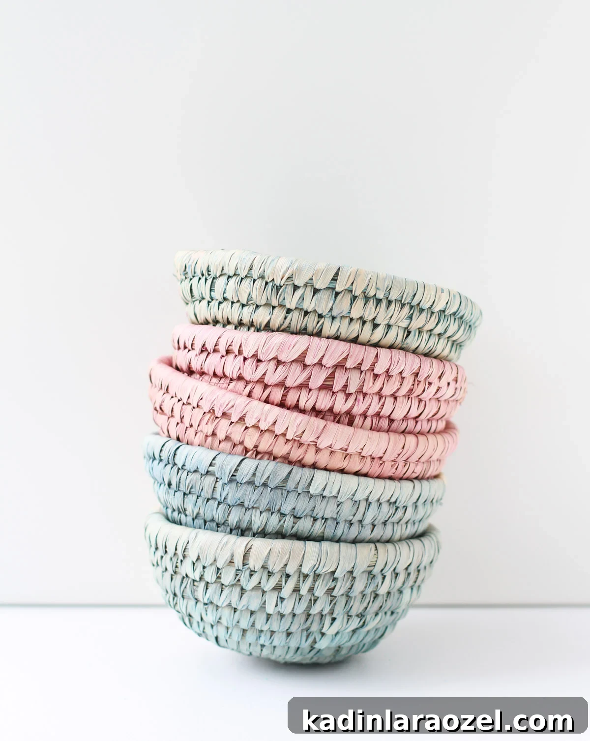 10-Minute Dip-Dyed Woven Baskets DIY Tutorial 5 Stacked woven baskets in muted pink, green, and blue