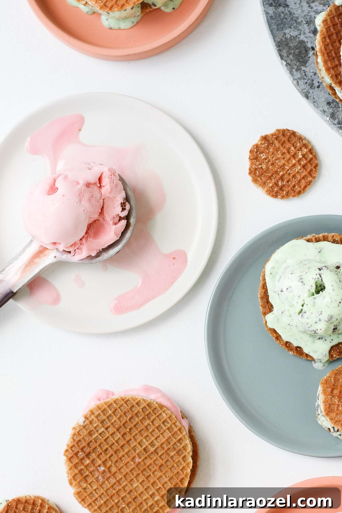 Stroopwafel Ice Cream Sandwich Recipe: Chewy Caramel Treats 3 Melted strawberry ice cream on a plate with waffle ice cream sandwiches on a white table