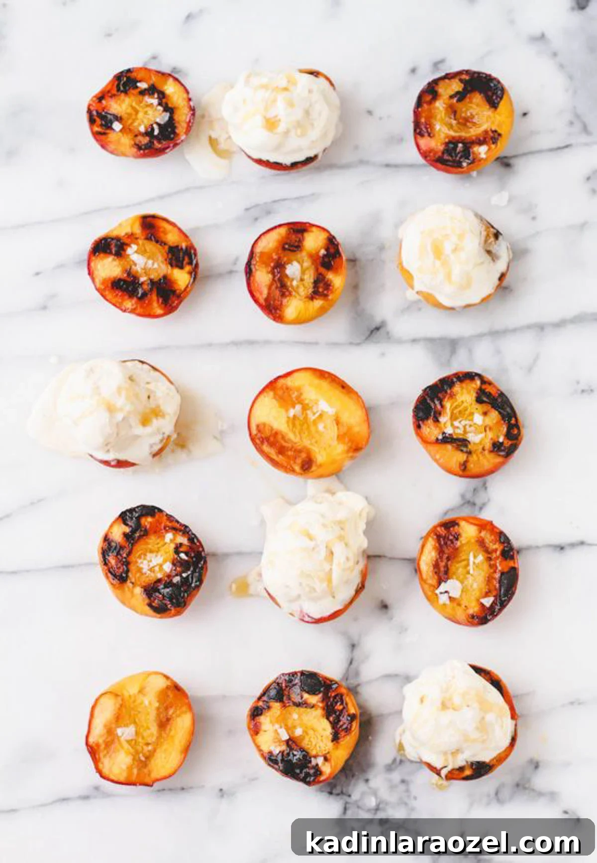 Grilled peaches, topped with vanilla ice cream and lined up in rows on a marble counter