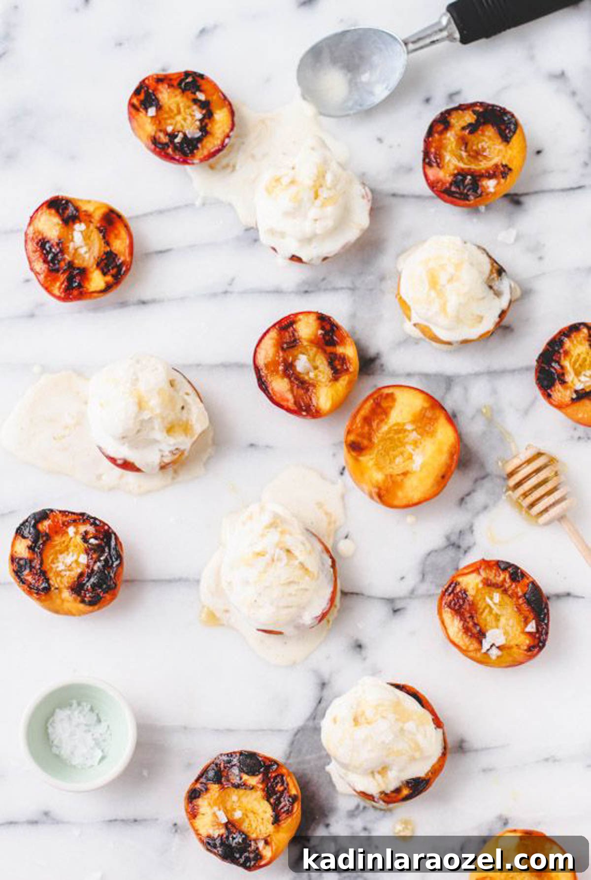 Grilled peaches on a marble counter with ice cream and honey