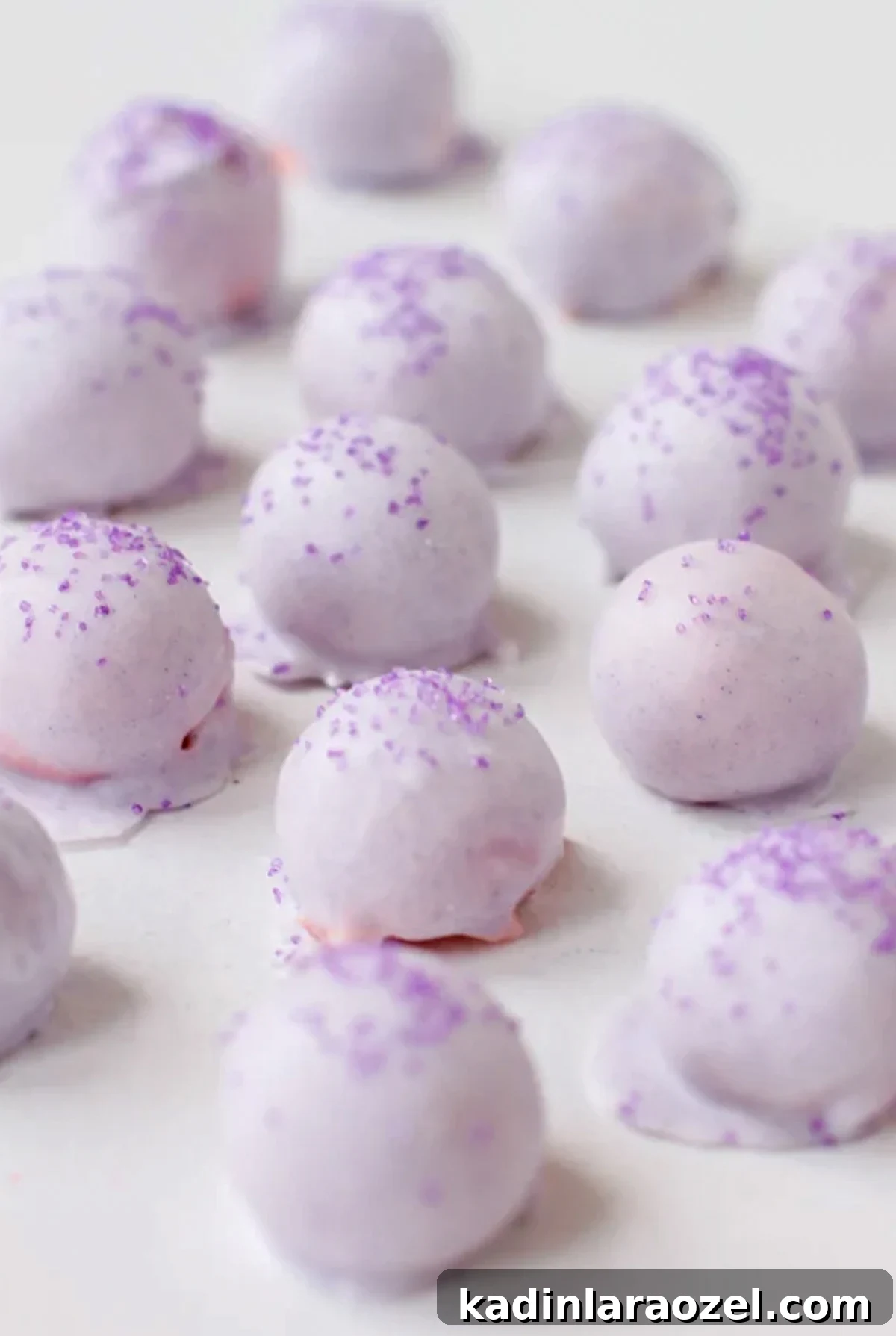 pastel purple cake balls all lined up on a white surface