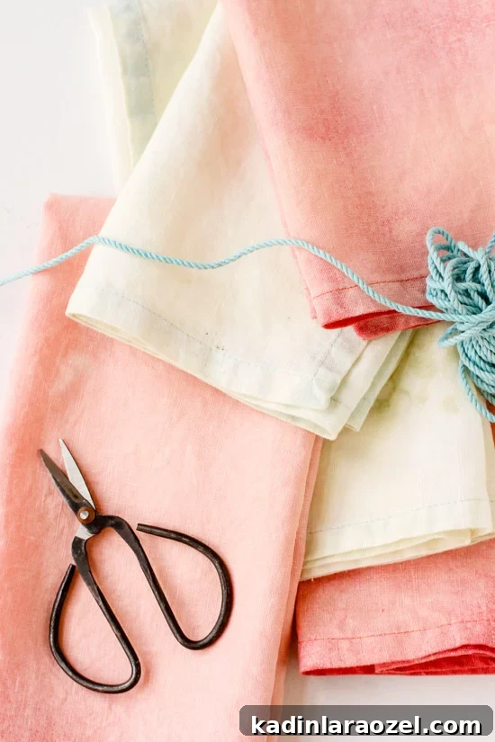 Stacked napkins in pastel colors with scissors and string.
