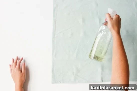 Spraying linen mint colored napkin with bleach for a lighter color textile.