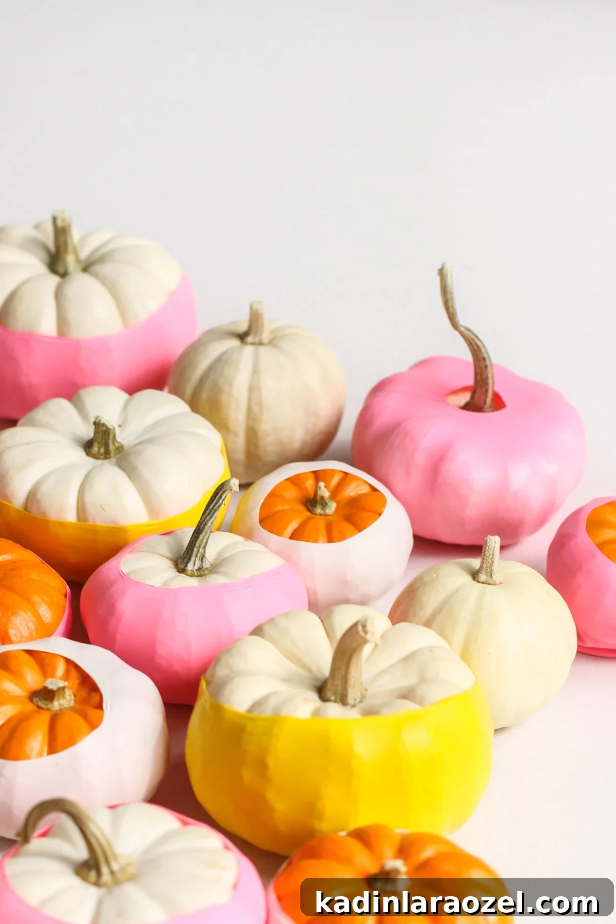 Bunch of small white pumpkins with brightly colored balloons pulled over them to create a dipped paint look