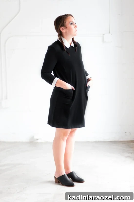 Woman is braided pigtails, wearing a black and white dress that looks like Wednesday Addams.