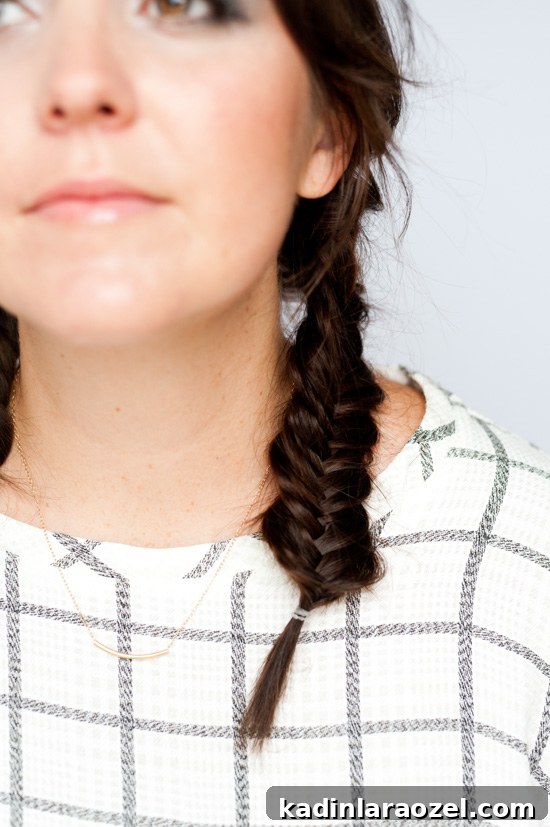 Closeup photo of fishtail braid pigtails on young woman with brunette hair.