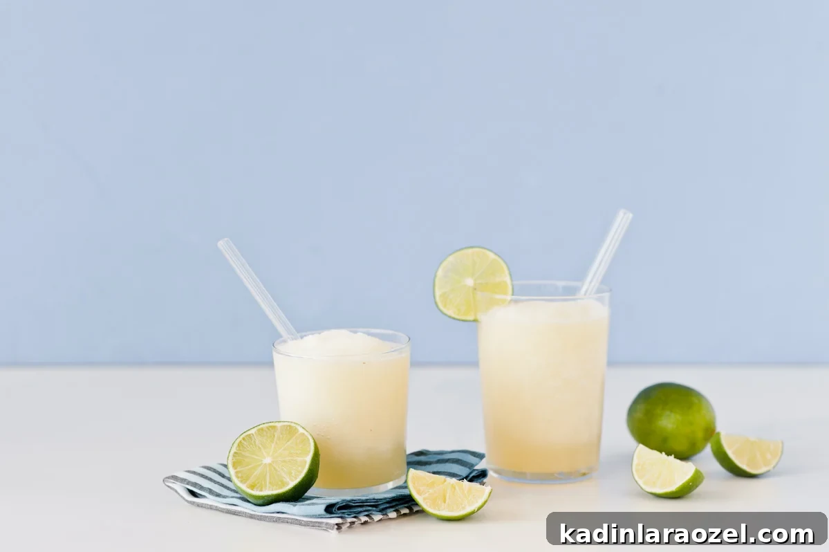 Gin and Juice Slushie Recipe: Refreshing Frozen Cocktail Guide 4 Two cocktails with limes on blue background with tropical vibes