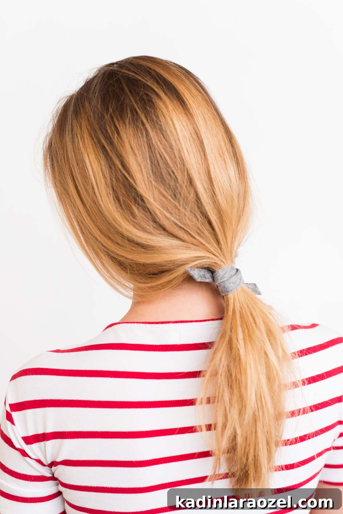Create a Sleek Ponytail in 3 Minutes Using Felt 3 Woman wearing low effortless ponytail with striped shirt