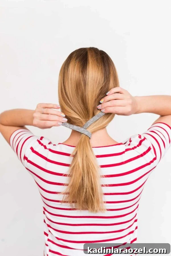 Create a Sleek Ponytail in 3 Minutes Using Felt 6 Woman tying her hair back in low ponytail