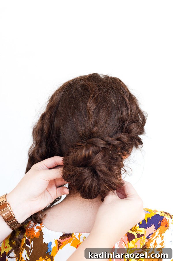 5-Minute Rope Twist Curly Updo Tutorial 7 Brunette woman putting her hair up in a twisted bun