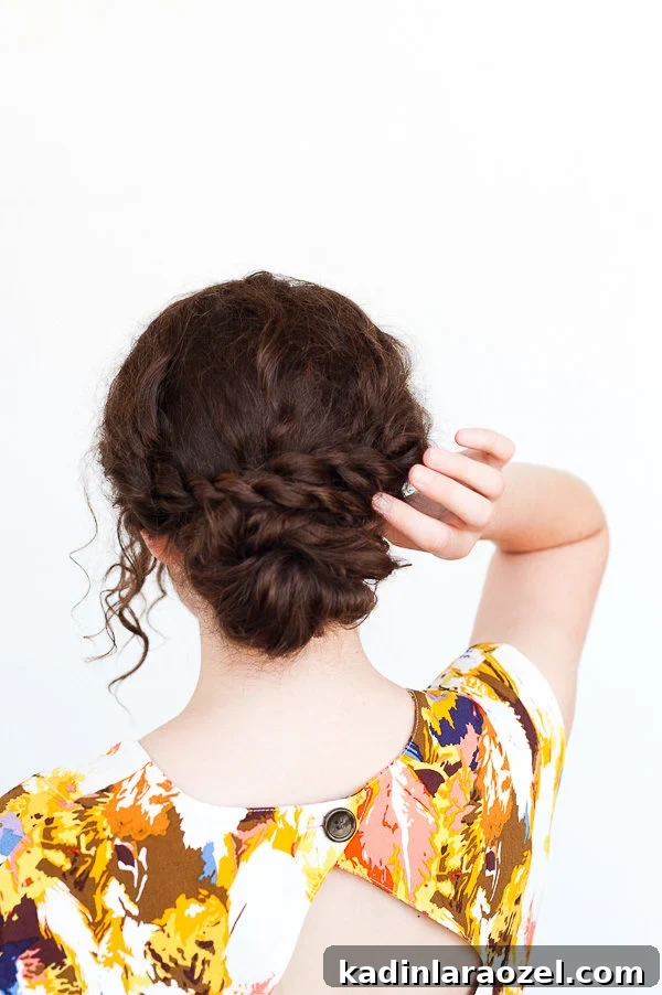 5-Minute Rope Twist Curly Updo Tutorial 8 Woman with brown curly hair, touching her hair in an updo