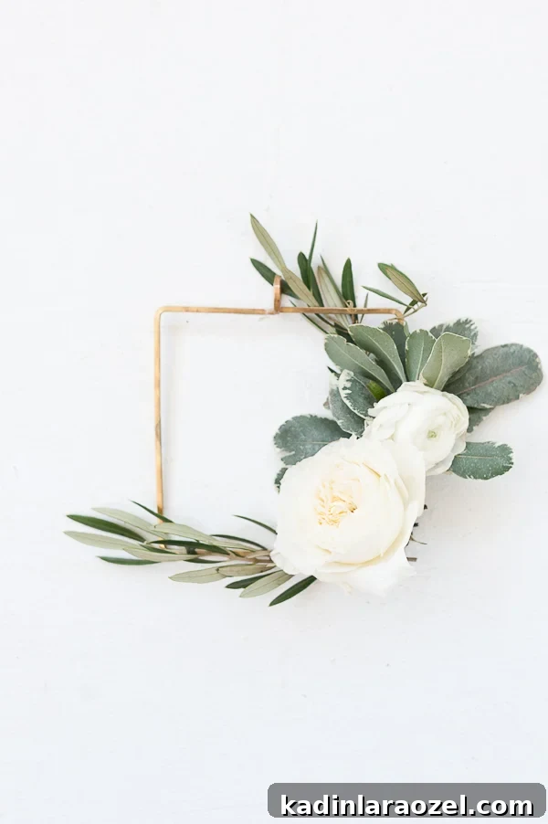 Create an Asymmetrical Wreath: Step-by-Step Design Guide 3 A white wreath with fresh garden roses, ranunculus, and olive branch greenery.