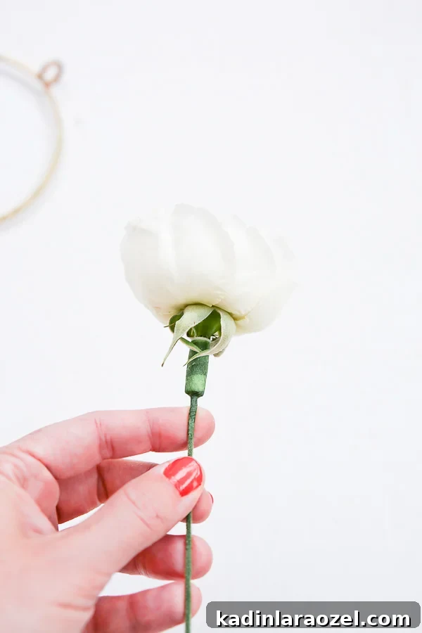 Create an Asymmetrical Wreath: Step-by-Step Design Guide 6 Adding floral stems to a white flower that needs support in a holiday wreath
