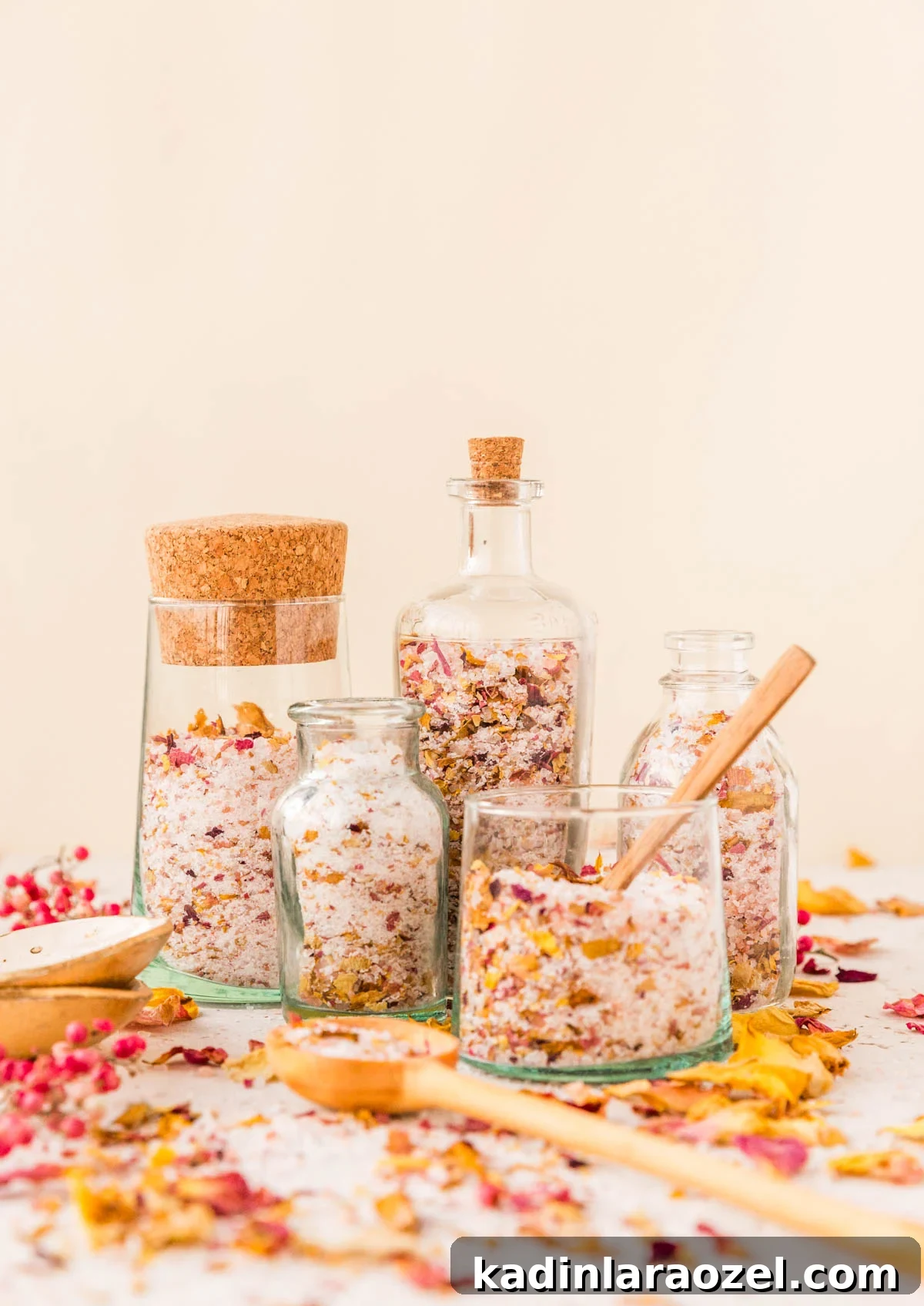 How to Dry Rose Petals and Make Rose Petal Bath Salts 12 glass jars filled with pretty rose petal bath salts, holding wooden spoons