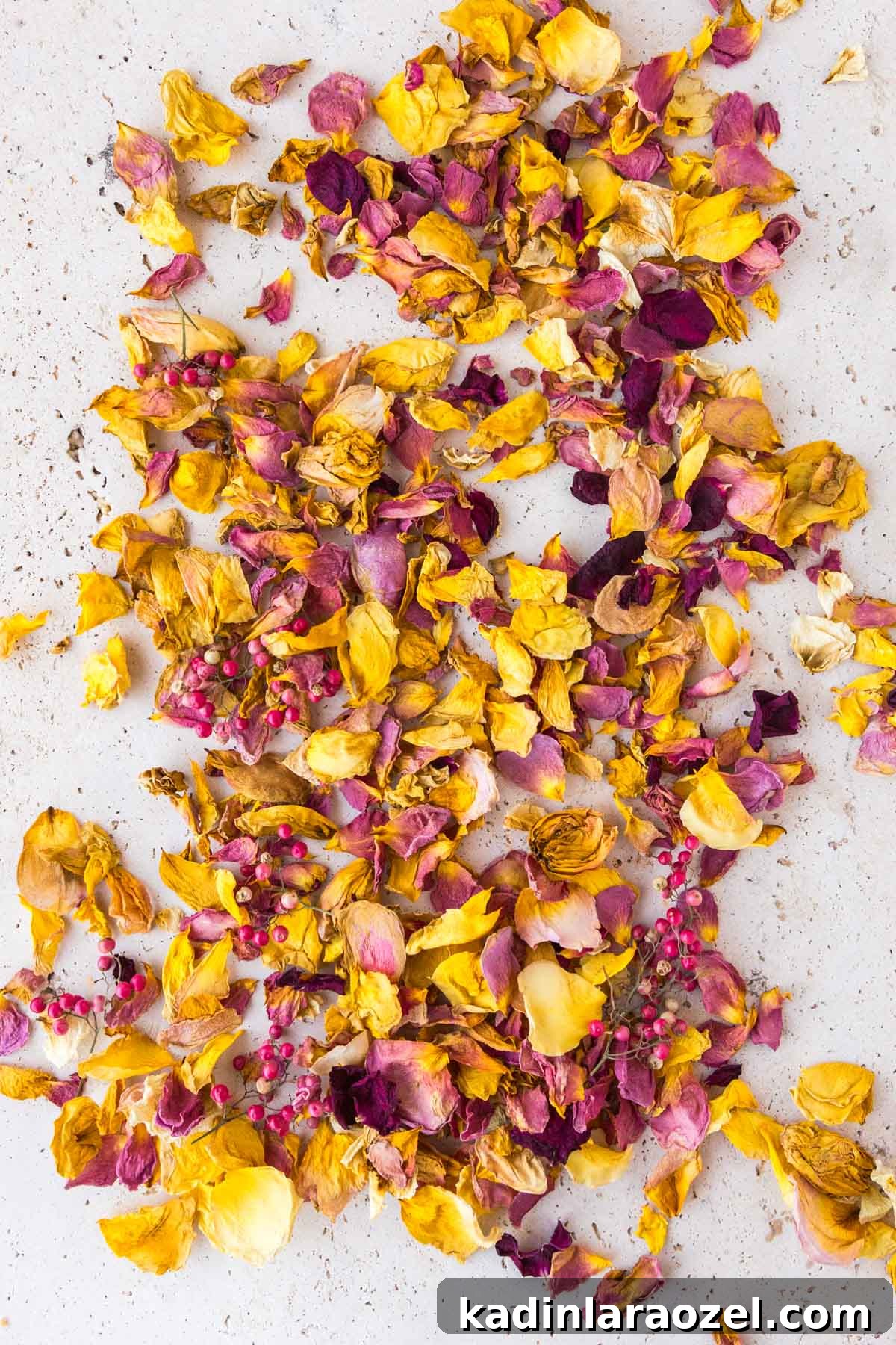 How to Dry Rose Petals and Make Rose Petal Bath Salts 5 dried rose petals in yellow, red, and pink laid out on travertine countertop
