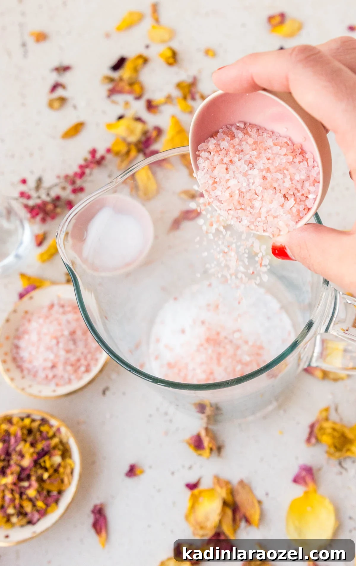 How to Dry Rose Petals and Make Rose Petal Bath Salts 7 pouring pink salt into glass beaker to make rose petal bath salts