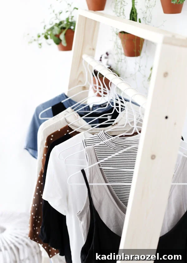49 Clever DIY Home Organization Ideas to Maximize Space 21 A wood clothing rack with white metal hangers hanging clothes from the clothing bar.