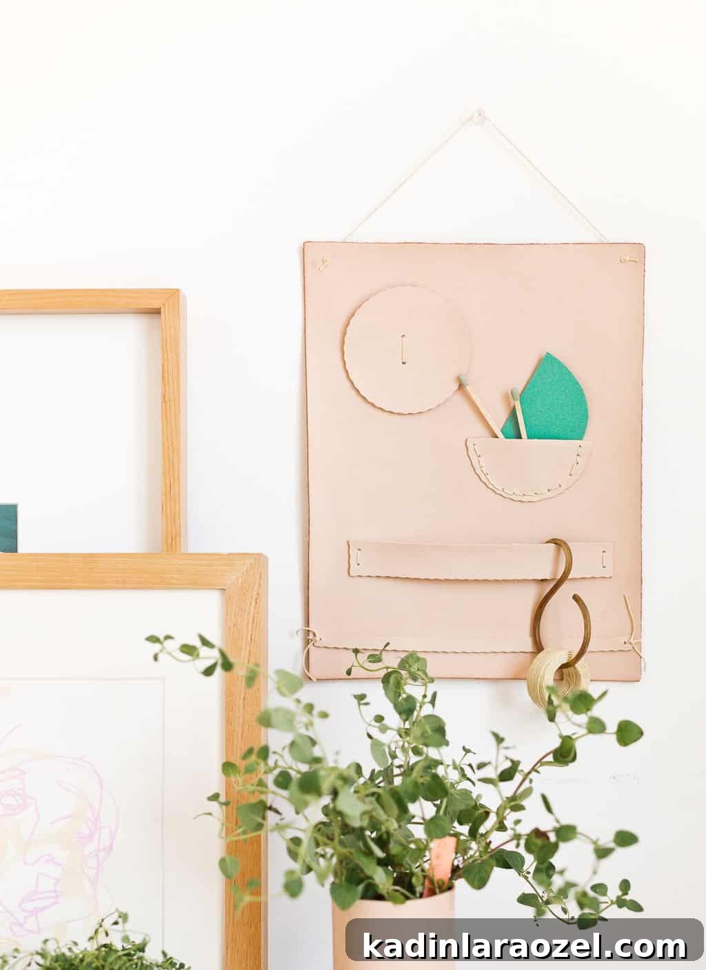 49 Clever DIY Home Organization Ideas to Maximize Space 39 A leather wall organizer hangs on the wall with plants surrounding it.
