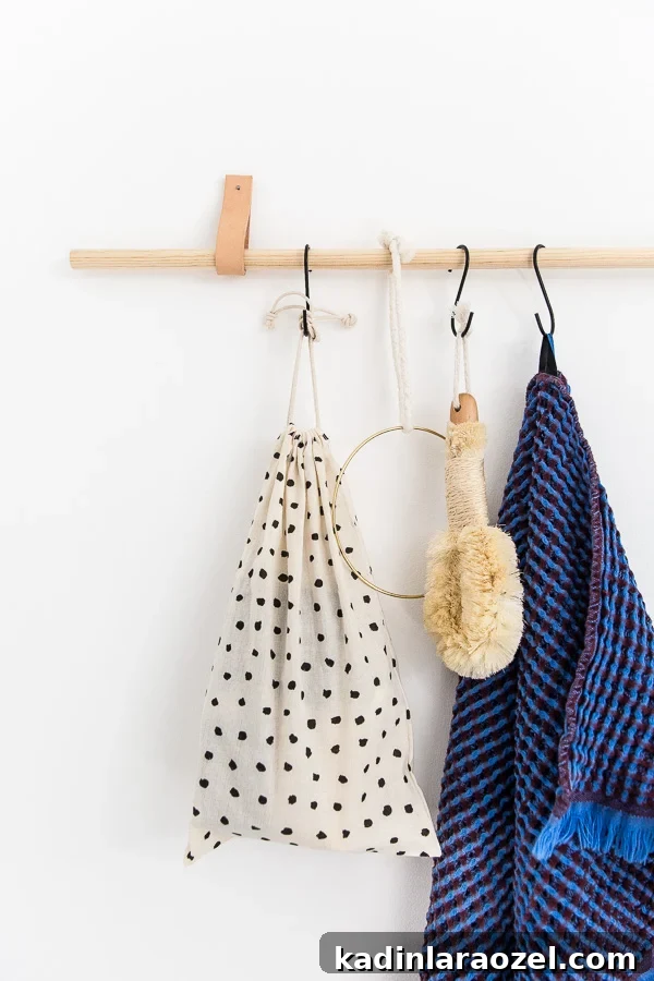 49 Clever DIY Home Organization Ideas to Maximize Space 46 A wood and leather organizer in the bathroom, with a blue waffle towel hanging from an S hook.