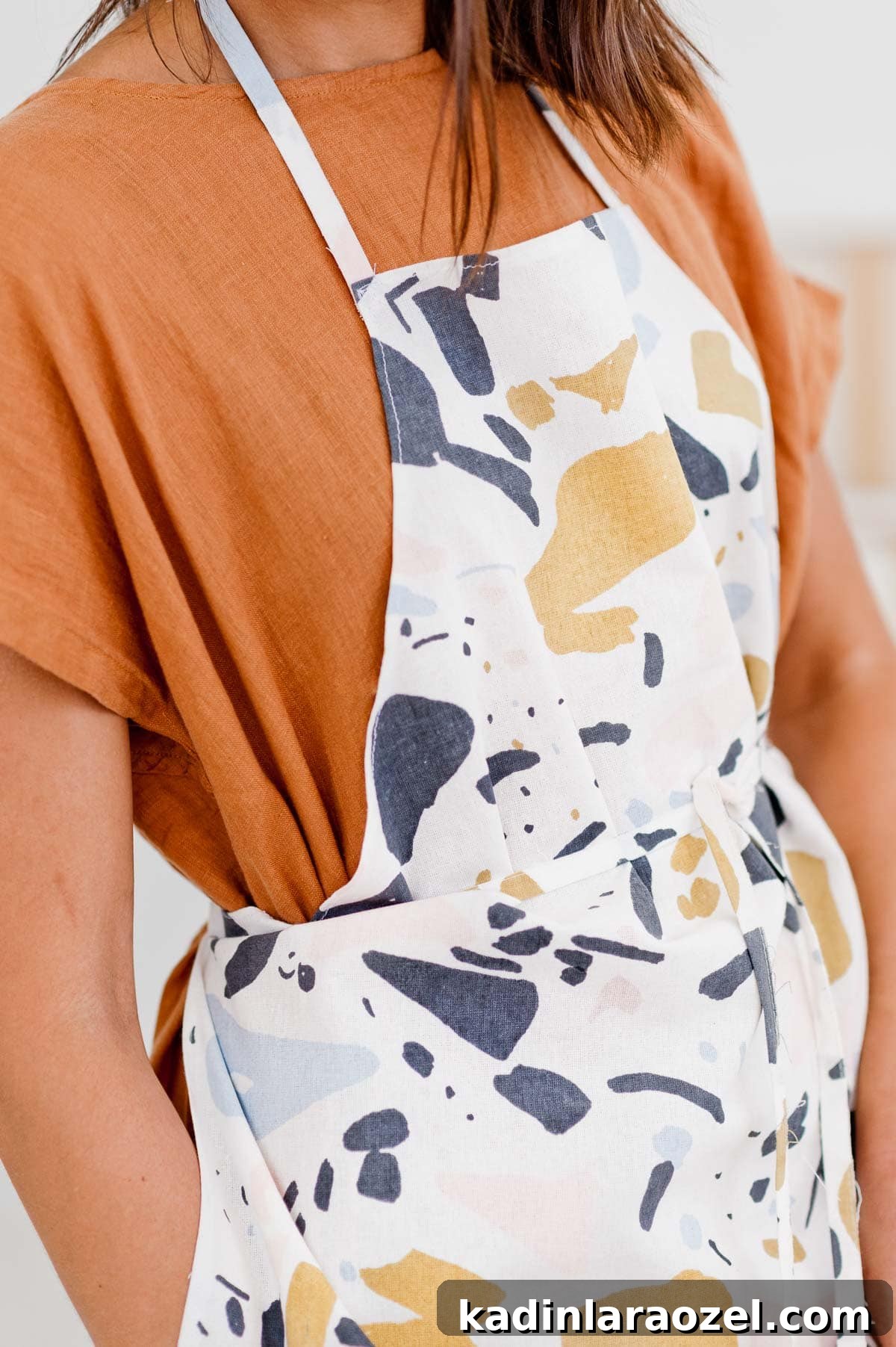 Hand sewn DIY apron on model wearing rust colored dress.
