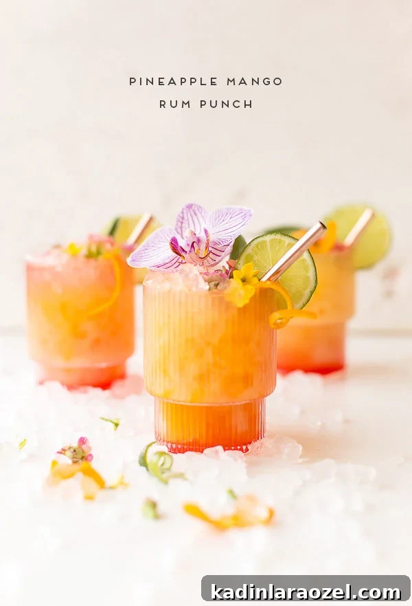 Pineapple mango rum punch recipe with lime slices and flowers on glass rim