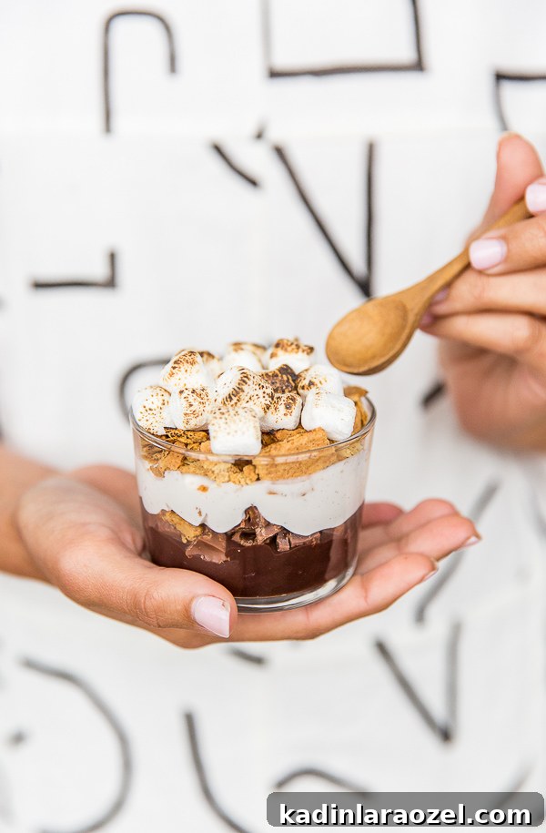 DIY S'more Cup being held in woman's hand with a wooden spoon