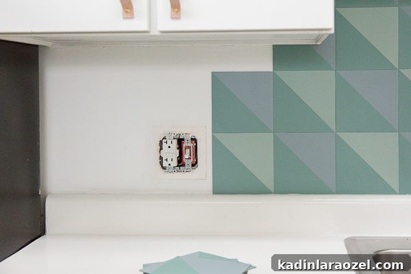 Install the DIY budget backsplash, using the painted pattern tiles you made.