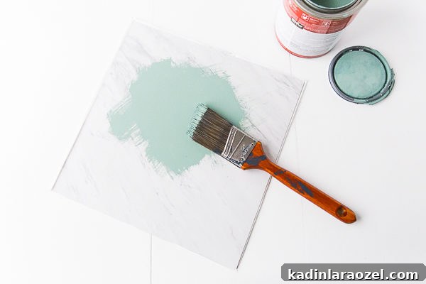 First, paint the vinyl tile a solid color with (matte finish) house paint.