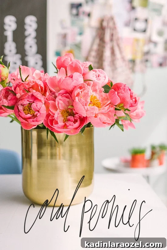 coral pink peonies in a large gold metal vase, sitting on white table
