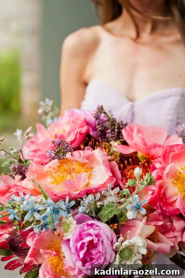 giant bridal bouquet with pink peonies and other colorful flowers, held by bridesmaid wearing wedding dress
