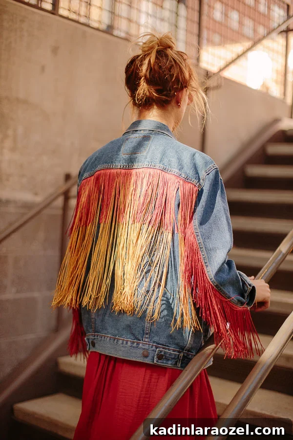 woman walking up stairs outdoors wearing a brick red dress and fringe jean jacket