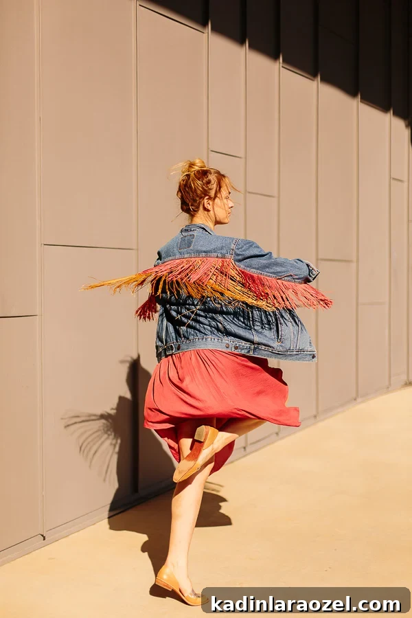 woman spinning in place outdoors, wearing a fringe jean jacket
