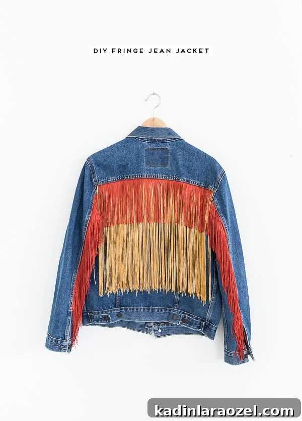 DIY fringe jean jacket on a hanger against a white wall