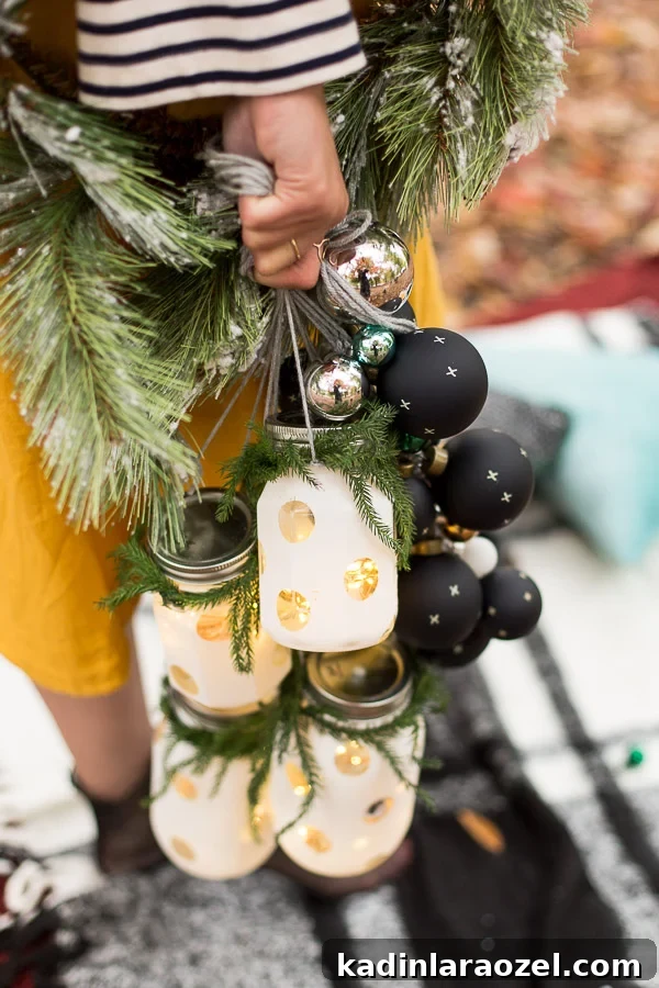 Woman holding polka dot white mason jar lanterns, with black and silver Christmas ornaments and holiday greenery
