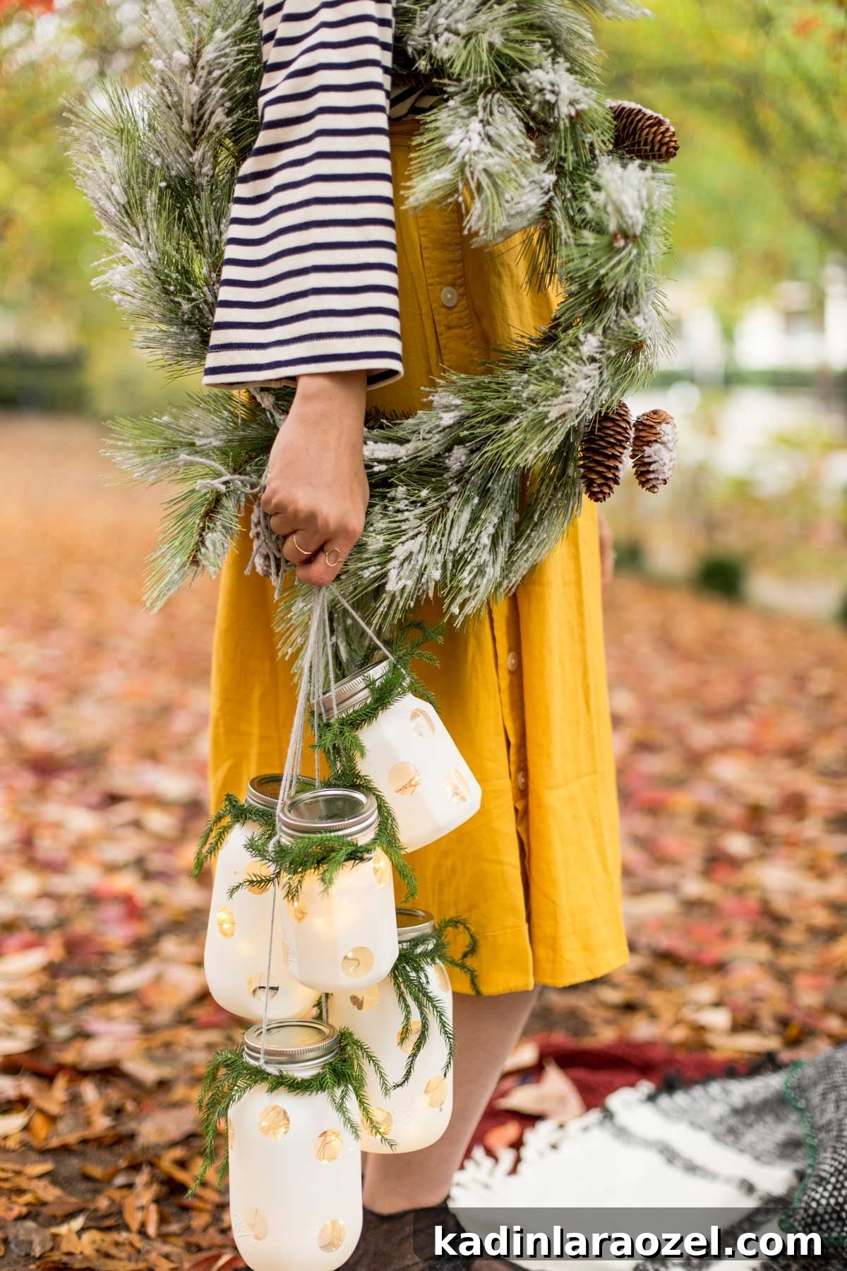 Woman holding polka hanging lanterns and a holiday wreath on her shoulder