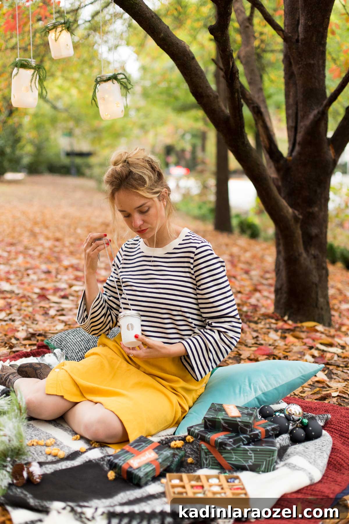 Woman sitting on a cozy winter picnic blanket with wrapped presents for Christmas