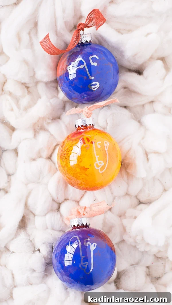 3 round, glass ornaments in blue and yellow with hand drawn faces, laying on fluffy white carpet