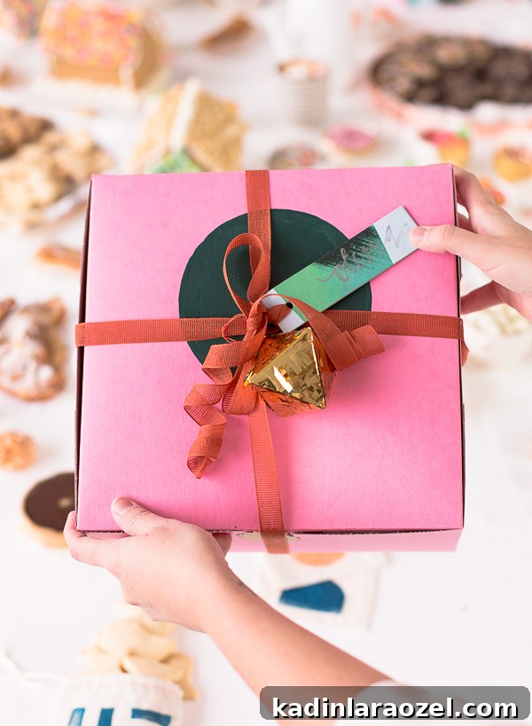 Cute packaging idea for holiday presents. A pink bakery box with a hand painted green circle, rust colored ribbon and a gold geo ornament.