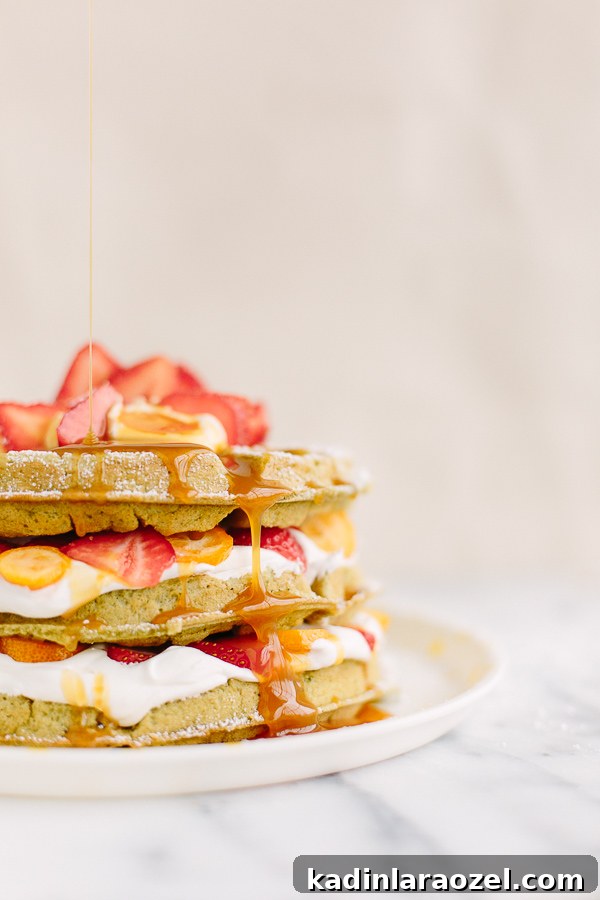 Matcha Waffles Recipe: Fluffy Green Tea Waffles with Crispy Edges 6 dripping syrup onto a stack of homemade waffles with fruit and whipped cream