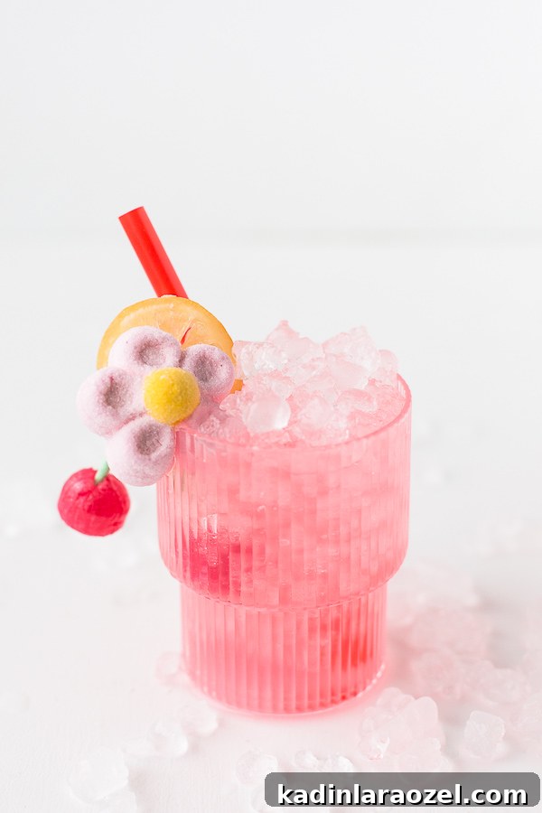 Candy-Coated Valentine’s Cocktail Recipes 4 Spiked cherry lemonade cocktails for Valentine's Day that are pink with flower and cherry candy garnish, sitting in ice