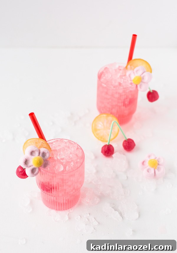 Candy-Coated Valentine’s Cocktail Recipes 5 Spiked cherry lemonade cocktails with candy and ice surrounding the pink drinks, in short cocktails glasses