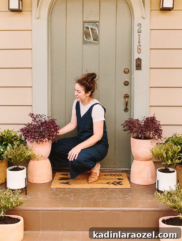Spring Porch Plant Ideas & DIY Totem Planters for Small Spaces 8 Image of woman kneeling down, caring for plants on front porch.
