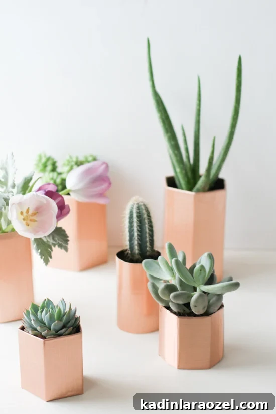 Faux copper geometric planters sitting on table, that hold succulents and flowers