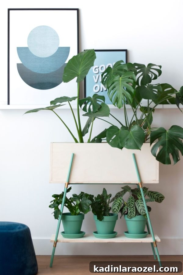 Green DIY plant stand and planters in a monochromatic color with artwork in the background.