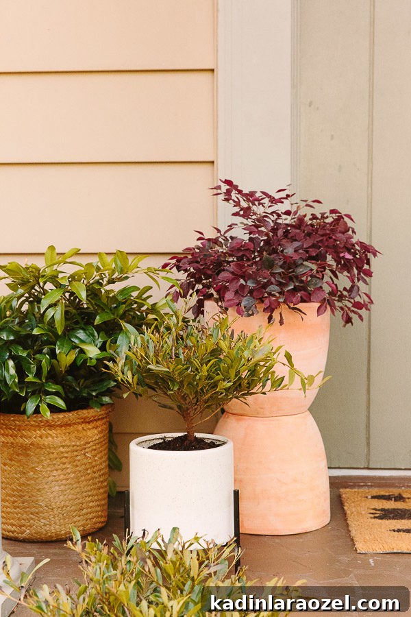 Terra-cotta totem planter by cottage front door, with fresh plants in each planter.