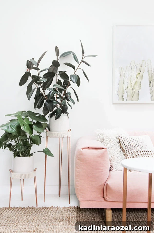 Copper planter stands next to a blush pink sofa in a white modern living room.