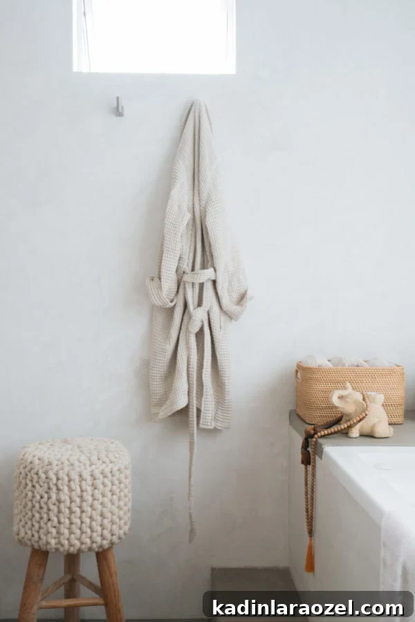 Minimal white bathroom with freestanding tub and wall hooks