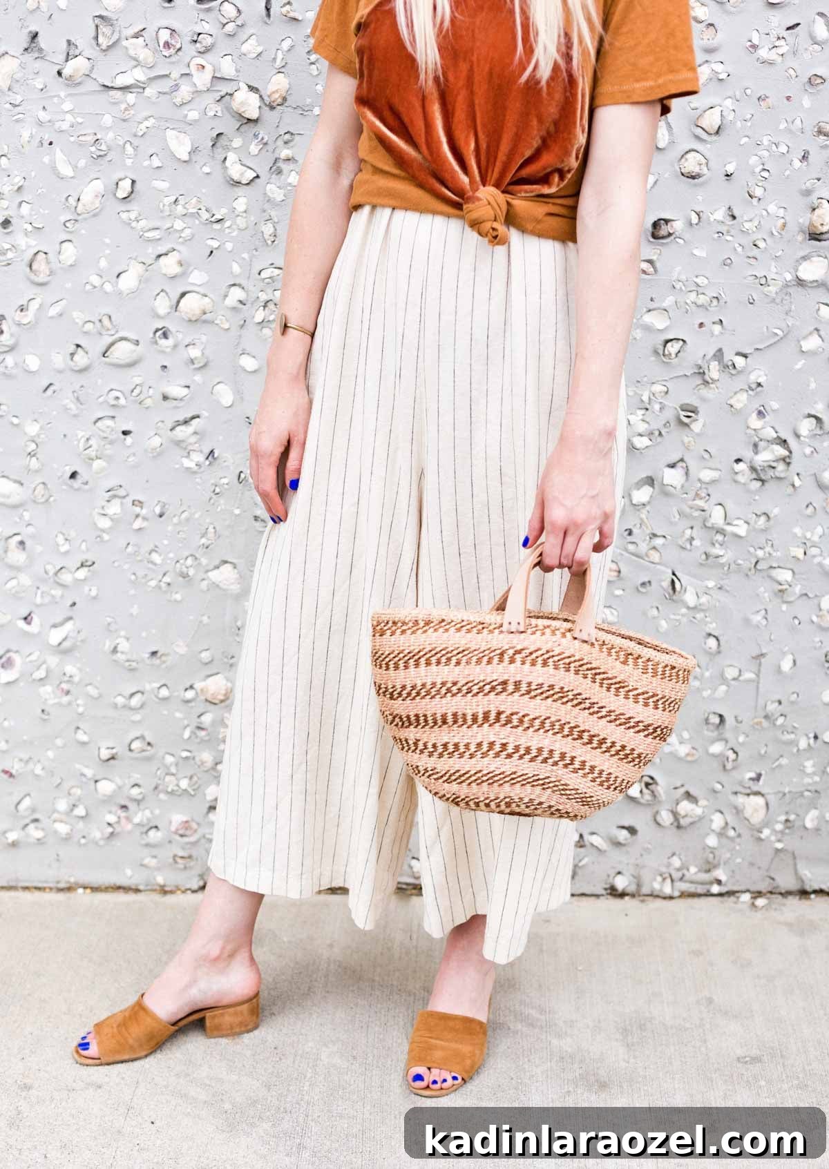 Woman wearing casual summer outfit and carrying a striped woven purse
