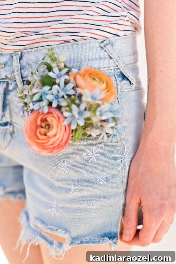 Closeup detail image of embroidered jean shorts with a firework star pattern.