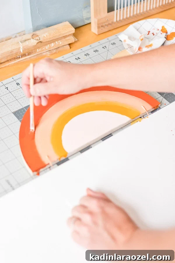 Painting an earth tone rainbow on a piece of wood shaped like a semi circle